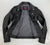 A close up of the lining on this classic black leather jacket with epaulets on the shoulders, high collar, zipped cuffs, adjustable belt, multiple pockets and a silver satin effect lining.